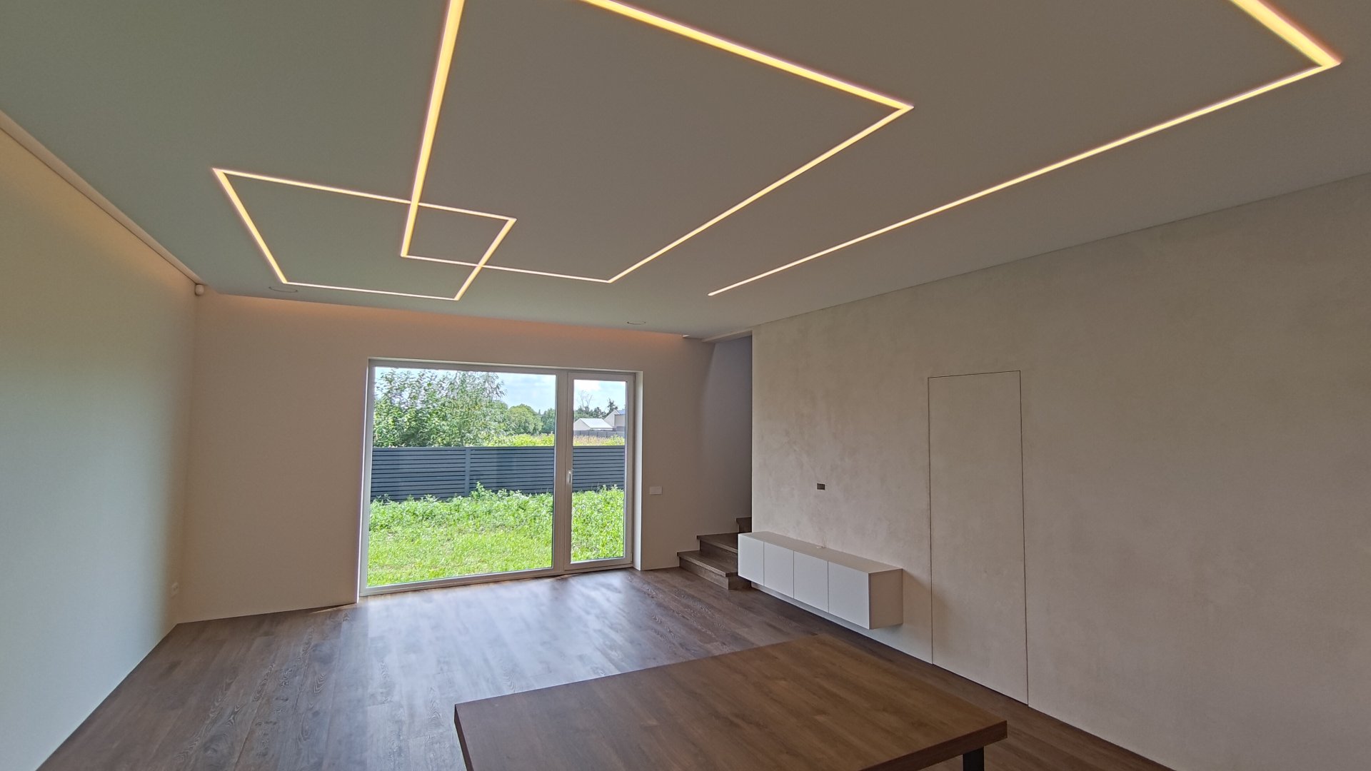 Kotedžo svetainė Aleksote su geometriniu LED apšvietimu ir paslėptomis durimis
